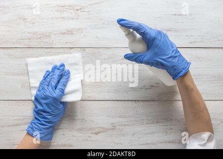 Oberflächenreinigung Sprühen antibakterielle Desinfektion Sprühflasche Desinfektion gegen COVID-19 Verbreitung tragen medizinische blaue Handschuhe. Stockfoto