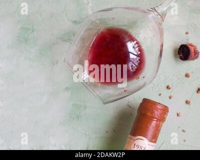 Auf dem Tisch liegen ein Glas alten Weines, eine Flasche und ein gebrochener Korken. Draufsicht. Stockfoto