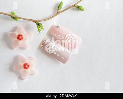 Frühjahrs-Maniküre. Spitzen mit rosa Frühlingsblumen-Design auf weißem Hintergrund. Stockfoto