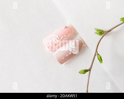 Maniküre im Sommer. Spitzen mit rosa Monogramm-Design auf weißem Hintergrund. Stockfoto