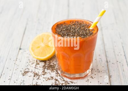 Karottencocktail mit Zitronen- und Chiasamen in einem Glas auf hellblauem Hintergrund, selektiver Fokus. Gesundes, leckeres Getränk Stockfoto