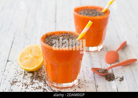 Karottencocktail mit Zitronen- und Chiasamen in einer Brille auf hellblauem Hintergrund, selektiver Fokus. Gesundes, leckeres Getränk Stockfoto