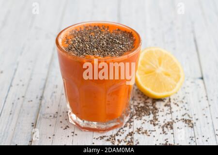 Karottencocktail mit Zitronen- und Chiasamen in einem Glas auf hellblauem Hintergrund, selektiver Fokus. Gesundes, leckeres Getränk Stockfoto