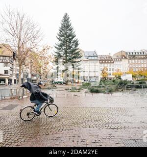 Straßburg, Frankreich - 3. Nov 2020: Älterer Radfahrer im Ort Kleber mit Weihnachtsbaum-Installation im Hintergrund auf fast leeren Straßen während der nationalen Sperre wegen COVID-19 Pandemie in Frankreich Stockfoto