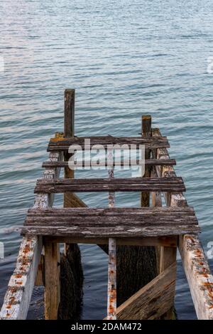 n alter, klappriger, verfaulter Holzsteg oder Pier, der als Landeplatz für kleine Boote am Meer in yarmouth auf der Insel wight genutzt wird. Stockfoto