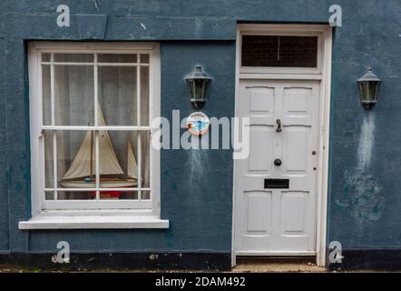 Die Eingangstür eines Cottage mit einem nautisch thematisierten Fenster mit einer großen Modellyacht in yarmouth auf der Insel wight, großbritannien Stockfoto