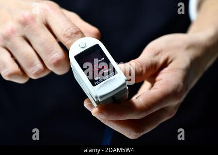 Eine Frau misst Sauerstoff in ihrem Blut mit einem nicht gebrandeten Oximeter Stockfoto