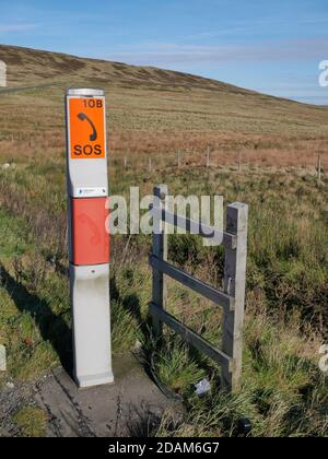 Moorland SOS Telefonpfosten grau mit zwei orange roten Schildern Mit schwarzen Buchstaben und Darstellung des Telefons auf Moor klein Holzzaun zur Seite Stockfoto