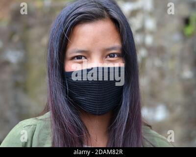 Schöne junge indische Monpa Mädchen bedeckt ihr Gesicht mit einer wiederverwendbaren, nicht-medizinische schwarze Gesichtsmaske. Stockfoto