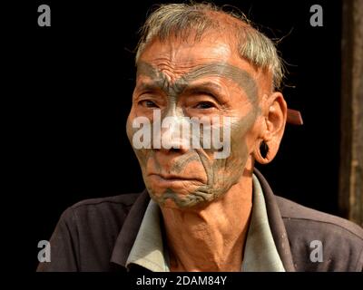 Alt pensionierten indischen Konyak Naga Krieger und Headhunter mit traurigen Augen, Tribal Gesichts-Tattoo und unverwechselbaren traditionellen Frisur Posen für die Kamera. Stockfoto