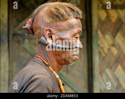 Alter Konyak Naga Krieger und Ex-Headhunter mit Gesichts-Tattoo, Tribal Frisur und Hirsch Hörner in seinen Ohrläppchen Posen für die Kamera (Profilfoto). Stockfoto