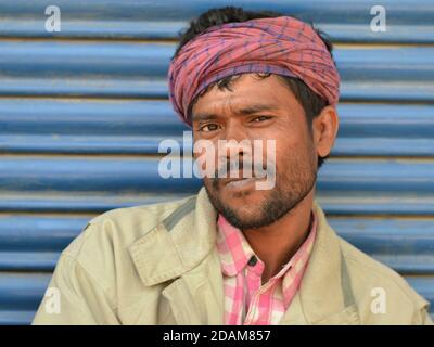 Die indische Wanderarbeiterin mittleren Alters trägt einen pinkkarierten Bandana-ähnlichen Kopfumhang und posiert für die Kamera. Stockfoto