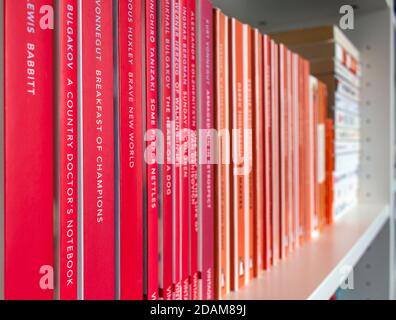 Regal mit klassischen orangefarbenen Pinguin-Büchern. Stockfoto