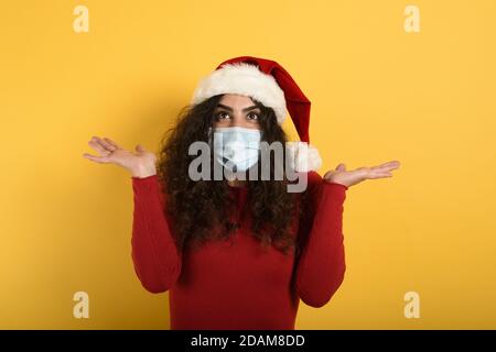 Frau mit Gesichtsmaske ist über etwas gewundert. Gelber Hintergrund Stockfoto