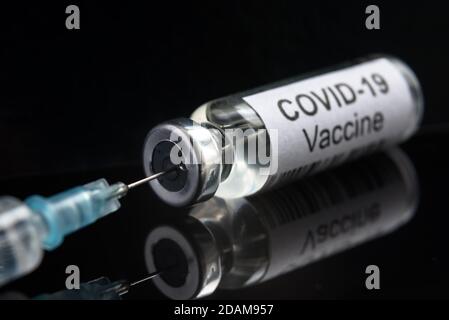 COVID-19-Impfstoff auf schwarzer Nahaufnahme, Spritze und Flasche mit Impfstoff für Coronavirus-Heilung. Konzept der Corona-Virus-Forschung, Behandlung, Injektion, Schuss Stockfoto
