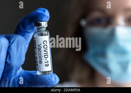 COVID-19 Impfstoff in der Hand Arzt Nahaufnahme, Forscherin mit Maske und Flasche mit Impfstoff für Coronavirus Heilung im Labor. Konzept klinischer Tri Stockfoto