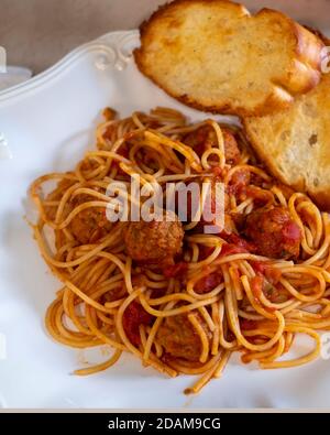 Gekochte Spaghetti und Fleischbällchen auf einem weißen Teller mit geröstetem Knoblauchbrot. Nahaufnahme. Stockfoto