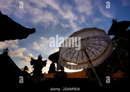 Silhouetten von Tempelgebäuden und hinterleuchtete Sonnenschirme an einem Tempel, während des Galungan Festivals. Ubud, Bali, Indonesien Stockfoto