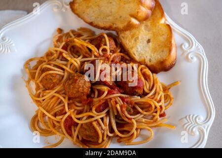 Gekochte Spaghetti und Fleischbällchen auf einem weißen Teller mit geröstetem Knoblauchbrot. Nahaufnahme. Stockfoto