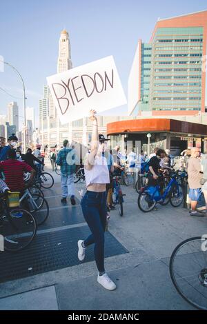 Frau, die in Menschenmenge mit 'Byedon'-Schild vor dem Barclays Center während der Feier des designierten Präsidenten Joe Biden, Brooklyn, New York, USA, läuft Stockfoto