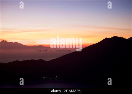 Blick in der Morgendämmerung über die Meerenge zwischen Lombok und Bali in Richtung Mount Rinjani auf Lombok vom Caldera-Rand des Mount Batur auf Bali. Indonesien. Stockfoto