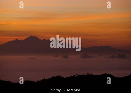 Blick in der Morgendämmerung über die Meerenge zwischen Lombok und Bali in Richtung Mount Rinjani auf Lombok vom Caldera-Rand des Mount Batur auf Bali. Indonesien. Stockfoto