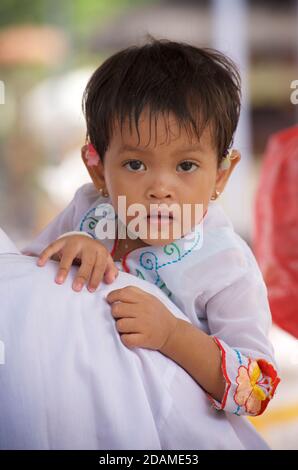 Balinesisches Mädchen in festlicher Kleidung, getragen vom Vater im Sakenan-Tempel, Bali, Indonesien für Galungan-Feierlichkeiten. Stockfoto