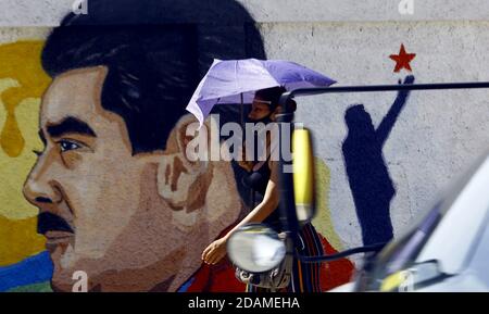 Guacara, Carabobo, Venezuela. November 2020. 13. November 2020. Eine Frau mit Regenschirm läuft vor Graffiti von Nicolas Maduro, Präsident von Venezuela. In Guacara, Carabobo, Venezuela . Foto: Juan Carlos Hernandez Kredit: Juan Carlos Hernandez/ZUMA Wire/Alamy Live News Stockfoto