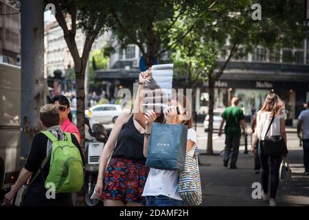 BELGRAD, SERBIEN - 9. JULI 2018: Zwei Mädchen stehen und beobachten entwickelte Filmnegativ aus analoger Fotografie in den Straßen, während sie einen Smar halten Stockfoto