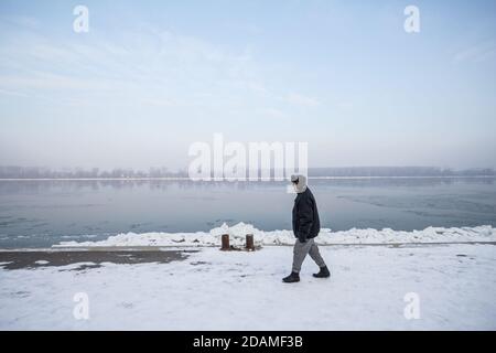 BELGRAD SERBIEN - 21. JANUAR 2017: Älterer Mann, der im Winter 2017 in Belgrad in der Nähe der gefrorenen Donau wanderte. Dieser Winter war particu Stockfoto