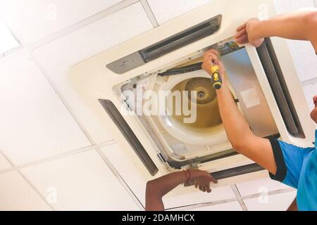 Techniker, der eine Kartusche für die Klimaanlage an der Decke instand hält und repariert Stockfoto