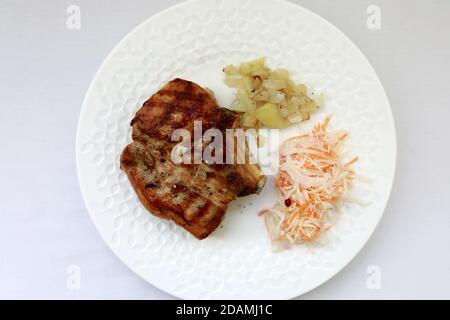 Weißer Teller mit gebackenem Schweinelende auf dem Tisch Stockfoto