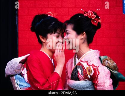 Zwei japanische Frauen in zeremoniellem Kleid Kimonos treffen sich auf einer Straße in Tokio, Japan. Stockfoto