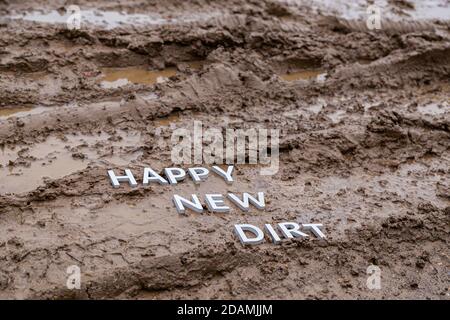 Die Worte glücklich neuen Schmutz gelegt mit silbernen Metall-Buchstaben Auf nasser Schlammoberfläche Stockfoto