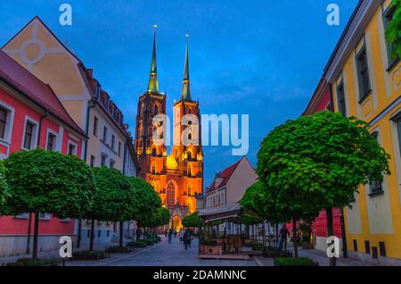 Straße mit Kopfsteinpflaster Straße, grüne Bäume, bunte Gebäude, Kathedrale St. Johannes der Täufer Kirche mit zwei Türmen und Lichter in der Altstadt historischen Stadtzentrum, Ostrow Tumski, Breslau, Polen Stockfoto