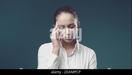 Junge professionelle Frau berührt ihre Tempel, sie leidet unter Kopfschmerzen Stockfoto