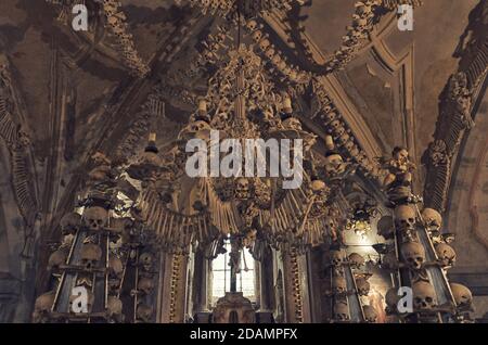 Kutna Hora, Tschechische Republik, 14. Mai 2019: Zimmer mit Kolonnade aus menschlichen Knochen und Schädeln. Knöcherner Glanz hängt von der Decke. Altar mit Kreuzigung Jesu Christi in der Kostnice-Kirche in Kutna Hora. Stockfoto