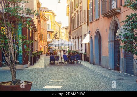 Brescia, Italien, 11. September 2019: Typisch italienische schmale Straße mit traditionellen alten Gebäuden, Kopfsteinpflasterstraße und Straßenrestaurant mit Sitzenden, historisches Stadtzentrum, Lombardei Stockfoto