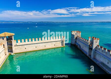 Sirmione, Italien, 11. September 2019: Kleiner befestigter Hafen mit türkisfarbenem Wasser, Scaligero Burg Castello Festung, Stadt am Gardasee, mittelalterliche Burg mit Steintürmen und Backsteinmauern, Lombardei Stockfoto