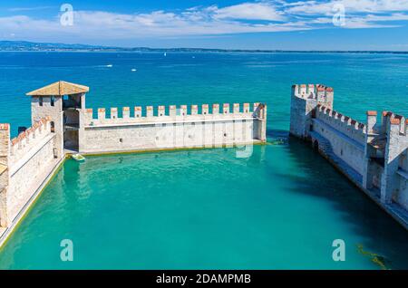 Sirmione, Italien, 11. September 2019: Kleiner befestigter Hafen mit türkisfarbenem Wasser, Scaligero Burg Castello Festung, Stadt am Gardasee, mittelalterliche Burg mit Steintürmen und Backsteinmauern, Lombardei Stockfoto