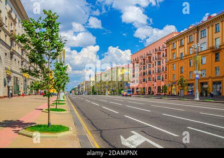 Minsk, Belarus, 26. Juli 2020: Unabhängigkeitsstraße mit sozialistischem Klassizismus Gebäude im Stalin-Empire-Stil, Bürgersteig und Reiten Autos und Busse, blauer Himmel weiße Wolken in sonnigen Sommertag Stockfoto