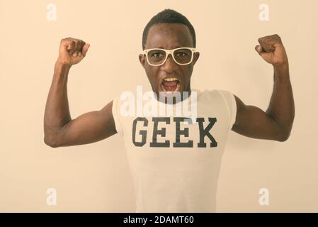 Studioaufnahme eines jungen schwarzen afrikanischen Nerds, der Geek trägt shirt, während seine Arme und zeigt Bizeps Muskeln gegen Weißer Hintergrund Stockfoto