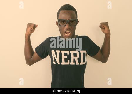 Studio-Aufnahme von jungen schwarzen afrikanischen Geek Mann trägt Nerd shirt, während er seine Arme beugt und Bizeps gegen Weiß zeigt Hintergrund Stockfoto