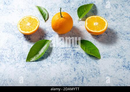 Orangen mit ihren Blättern auf blauem Hintergrund Stockfoto