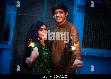 Fröhliche junge indische Paar feiern diwali Festival genießen Sparklers Feuerwerkskörper als Teil der Feier und Feiertage, tragen tradit Stockfoto