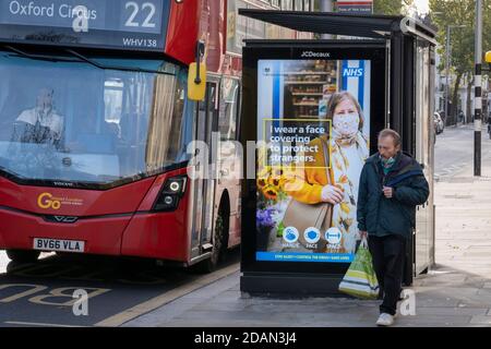 Während der zweiten Sperrung der britischen Coronavirus-Pandemie, bei der alle außer wichtigen Einzelhändler und Unternehmen am 13. November 2020 in London, England, nach den Beschränkungsregeln der Regierung geschlossen bleiben, laufen die Käufer an einer NHS (National Health Service)-Busschutzanzeige auf der King's Road vorbei. Stockfoto