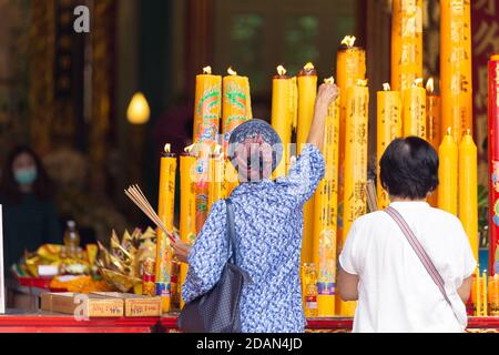 Asiatische Thailänder beten den Buddha im Guan Yin Thien Fah Schrein mit Blumen, Weihrauch und großen Kerzen an. Chinesische Tempel ist eine berühmte touristische destina Stockfoto