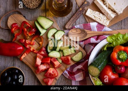 Zutaten für einen Gemüsesalat - Tomaten, Gurken, Feta-Käse, geschnittenes Gemüse. Salat wird zubereitet Stockfoto