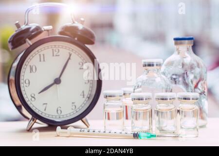 Zeituhr mit Medikamentenflaschen für Zeiten zur Gesundheitsversorgung oder Impfstoffplan Konzept. Stockfoto