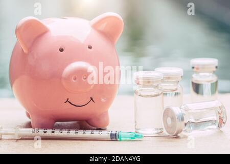 Medizinische Dosis Spritze mit Sparschwein für Geld sparen für die Gesundheitsversorgung und zahlen für Anti Corona (Covid-19) Virus-Impfstoff-Konzept. Stockfoto